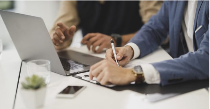 Twee mensen zitten samen voor laptop en maken notities