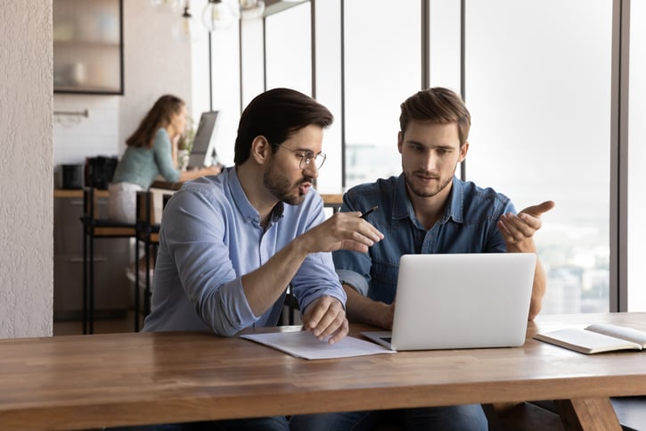 Zwei Mitarbeiterinnen teilen sich einen Schreibtisch und arbeiten im Modell der Arbeitsplatzteilung (Job Splitting), um die Vorteile des Jobsharing-Konzepts für Flexibilität und Produktivität zu nutzen.