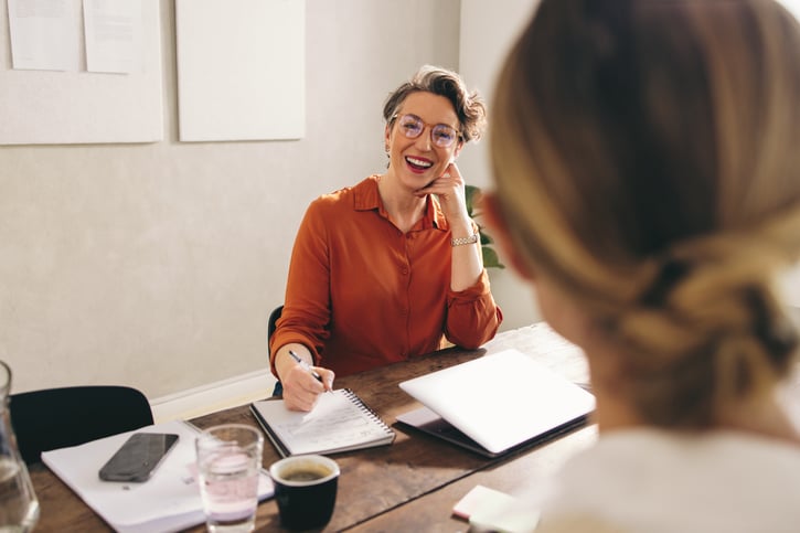 Vrouw zit aan bureau en lacht