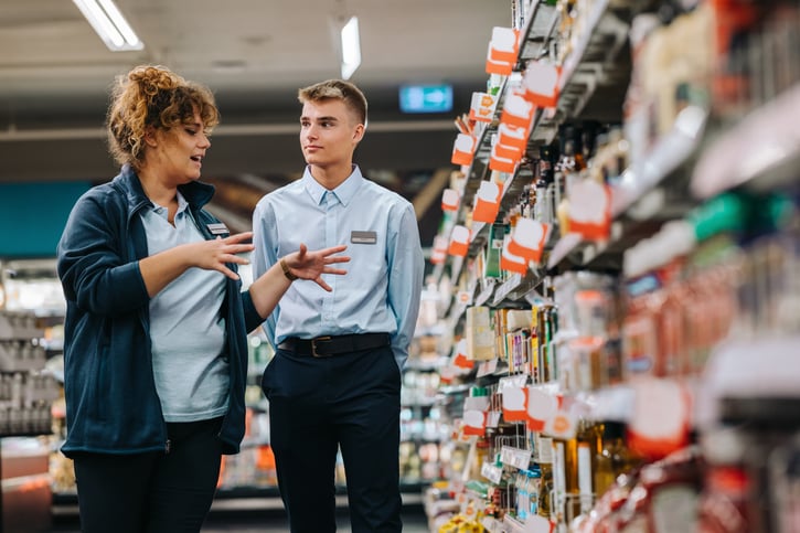 Un gerente de tienda o minorista entrenando a un nuevo empleado, simbolizando el proceso de oboarding
