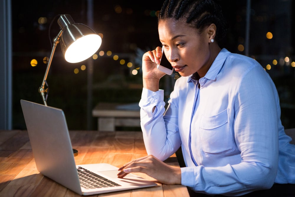 Businesswoman talking on mobile phone while working on laptop in the office-1