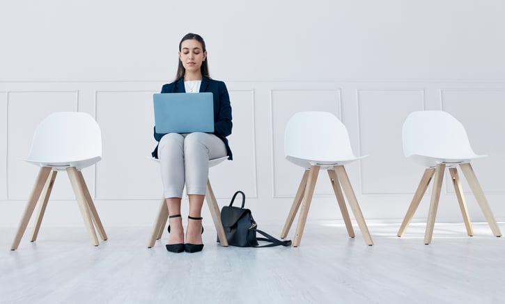 Candidate waiting in room for a job interview while working on laptop on her lap