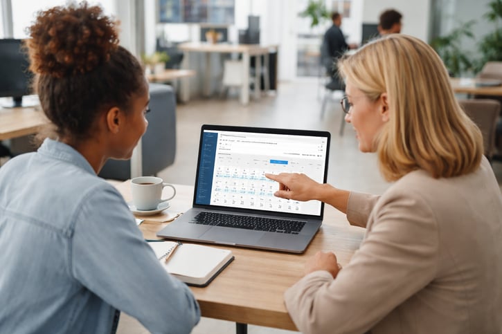 HR manager reviewing online timesheet software dashboard with a team member.