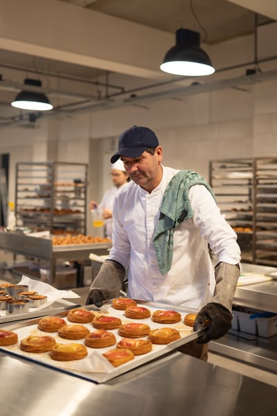 Alex Hoare Chatwick in der Backstube von Chatwick Coffee & Bakery, mit einem Tablett frisch gebackener Plunderteilchen.