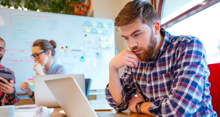 Man kijkt geconcentreerd naar laptop op bureau
