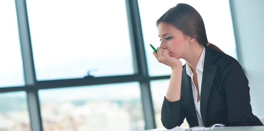 Vrouw kijkt bezorgd naar bureau en bedekt har neus en mond met een halfopen hand