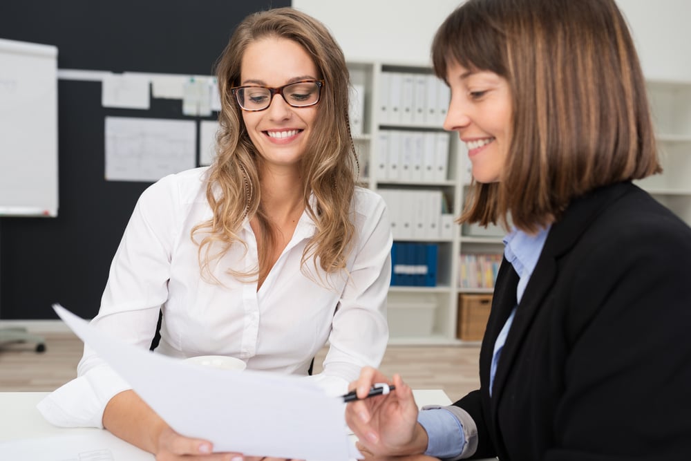 Close up Two Happy Young Businesswomen at the Office Talking About Business Report on Paper.-1