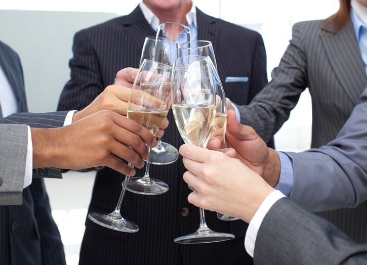 Mensen in pak staan in een cirkel en proosten met glazen champagne