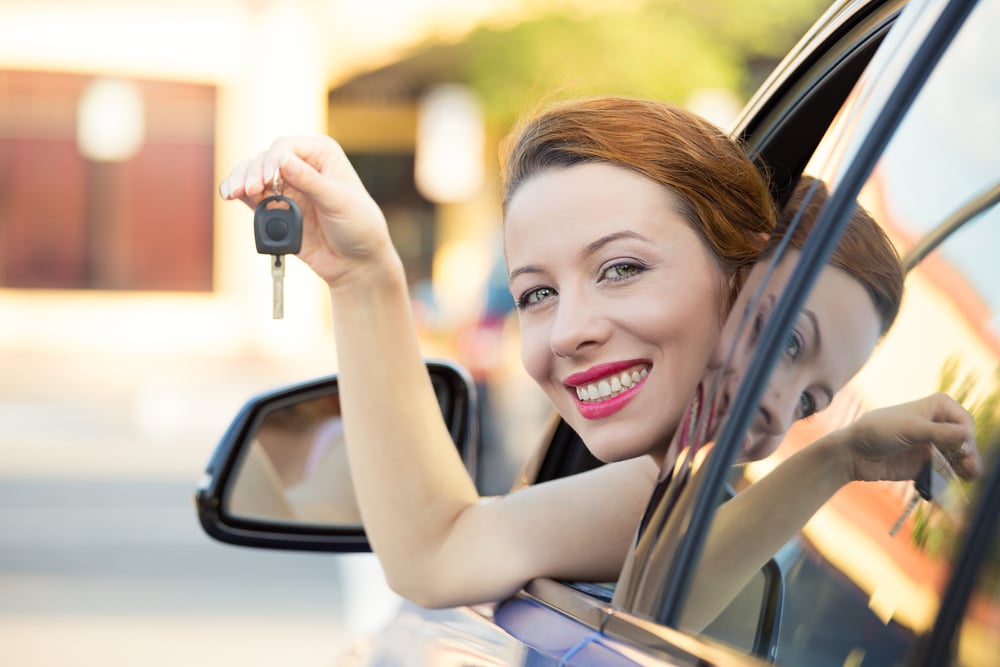 Jeune femme souriante assise dans sa voiture, illustrant l’avantage en nature véhicule de société