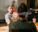 Man en vrouw zijn in gesprek. We kijken over de schouder van de vrouw mee en zien haar gesprekspartner, die niet in focus is.