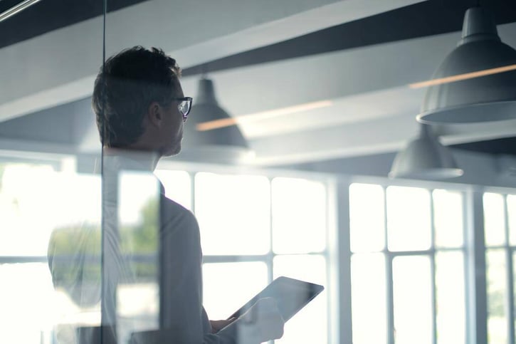 Creative shot of male employee standing in meeting room with iPad in hand