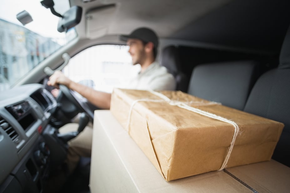 Delivery driver driving van with parcels on seat outside the warehouse, driver scheduling