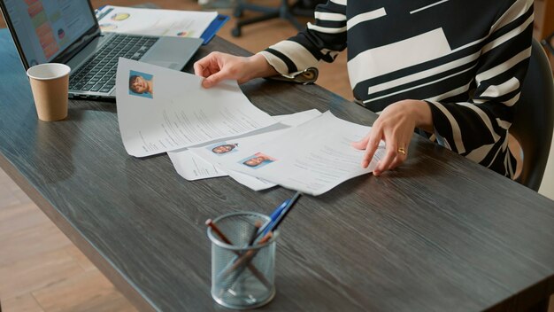 Ein Arbeitgeber der sich sorgfältig auf ein Bewerbungsgespräch vorbereitet indem er Bewerbungsunterlagen auf seinem Schreibtisch überprüft