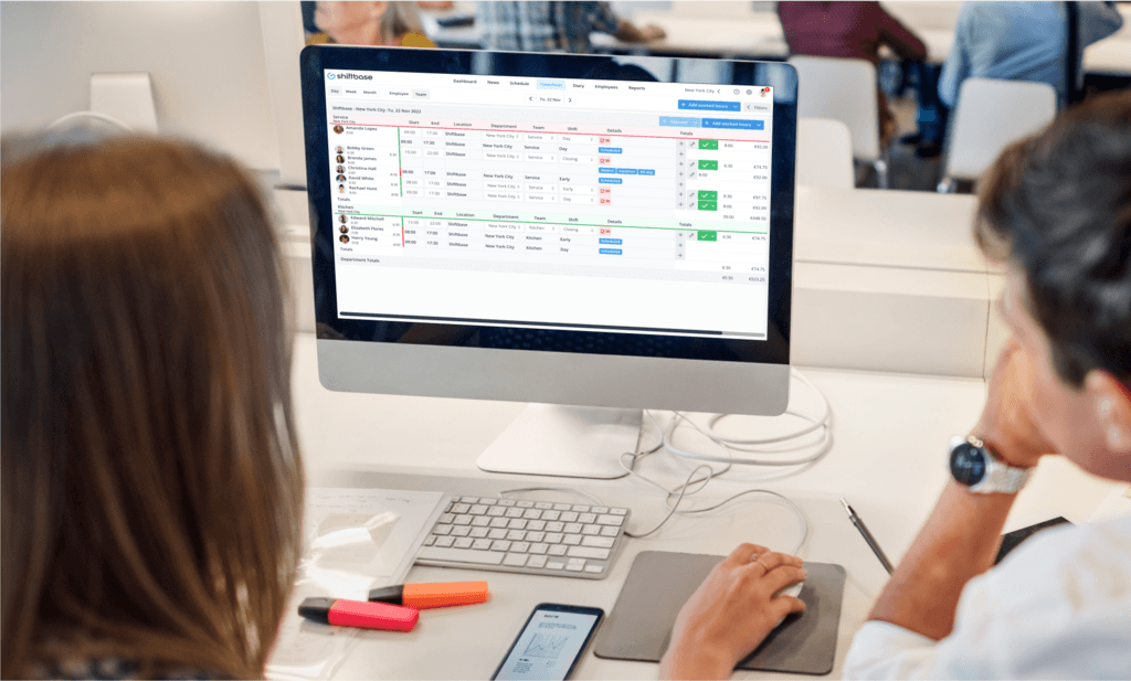 Empleados mirando la pantalla de la computadora, creando horarios de empleados en la herramienta de programación Shiftbase