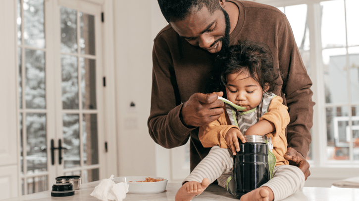 Padre alimentando a su hijo en casa durante el permiso de lactancia