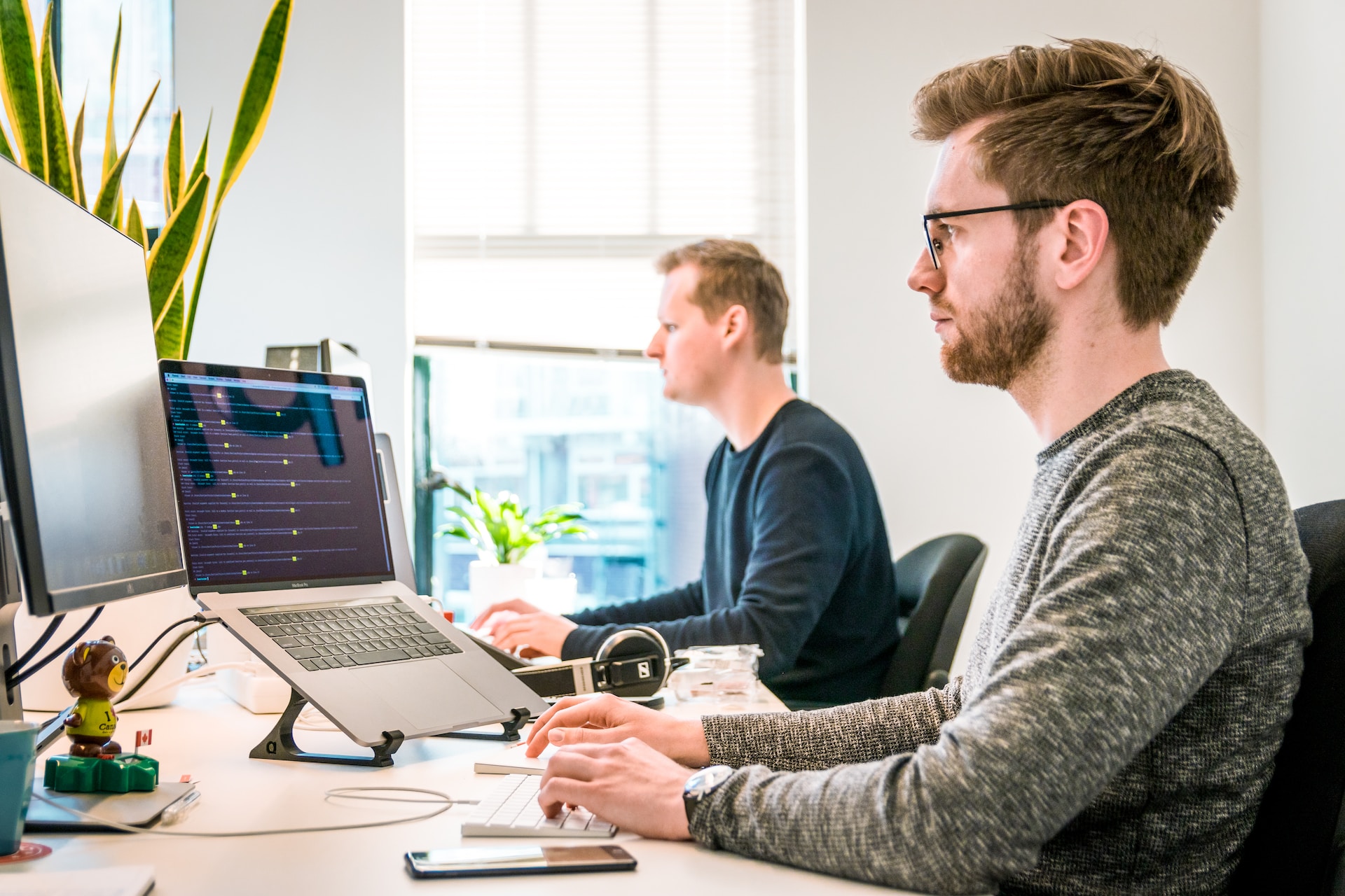 Compañeros de trabajo masculinos enfocados trabajando en sus computadoras portátiles en el lugar de trabajo