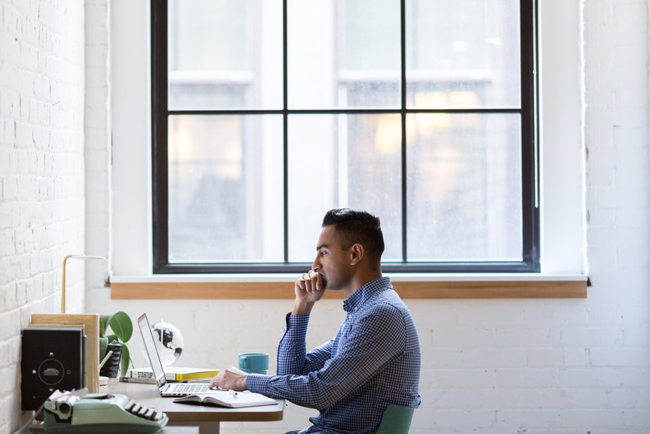 Zijaanzicht van man die aan zijn bureau zit en bezorgd kijkt