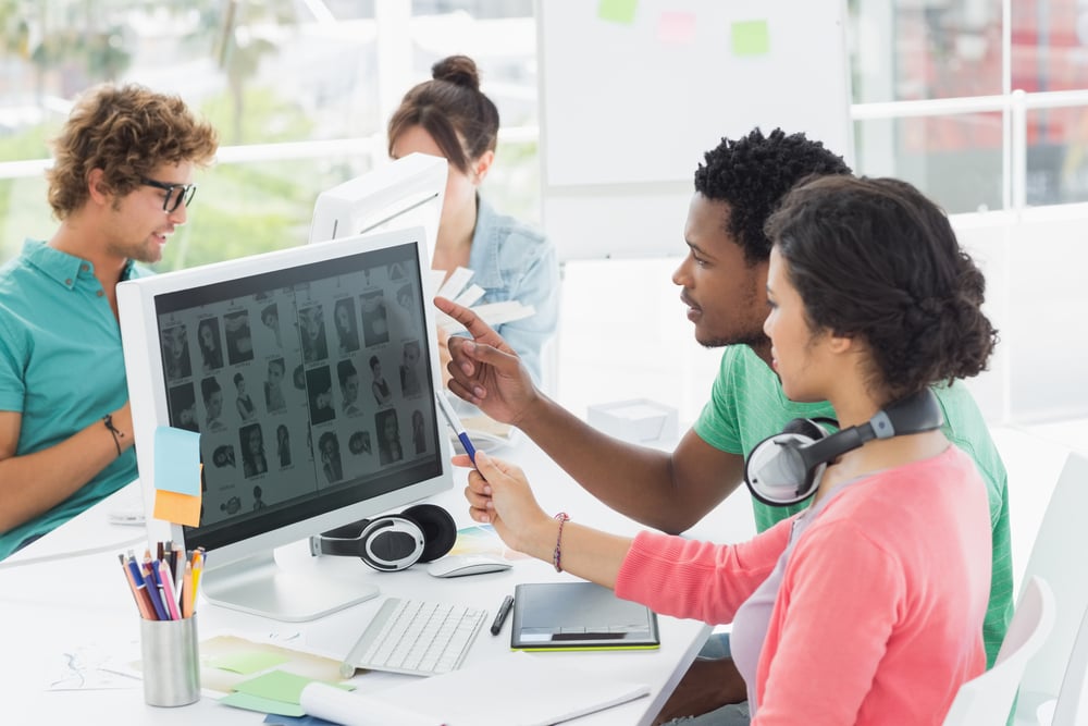 Group of casual young men and women working on computers in a bright office-1