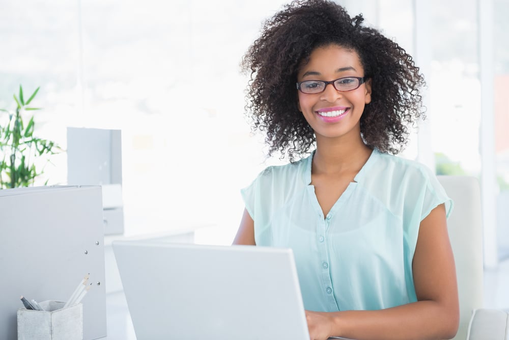 Happy hipster businesswoman working on laptop in her office