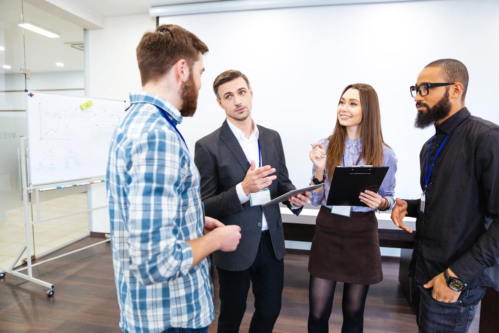 Head of department standing and talking to smiling young employees in office-1