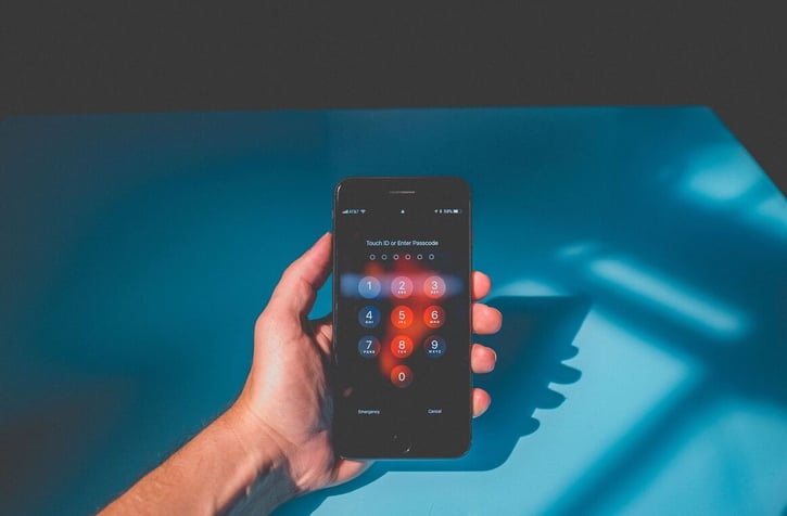 Hand houdt iPhone vast. Op het scherm is de lockscreen te zien.