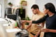 Male and female employees working behind a retail clothing store's counter, looking at data on computer