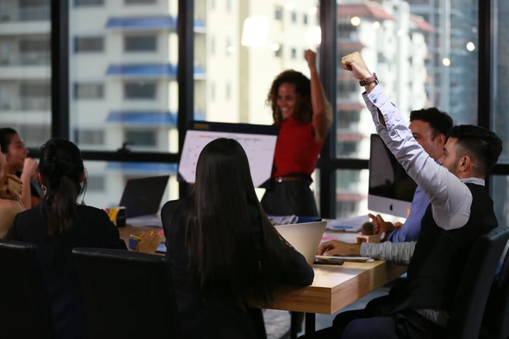 Mix race women present employee benefits plan to coworkers in meeting