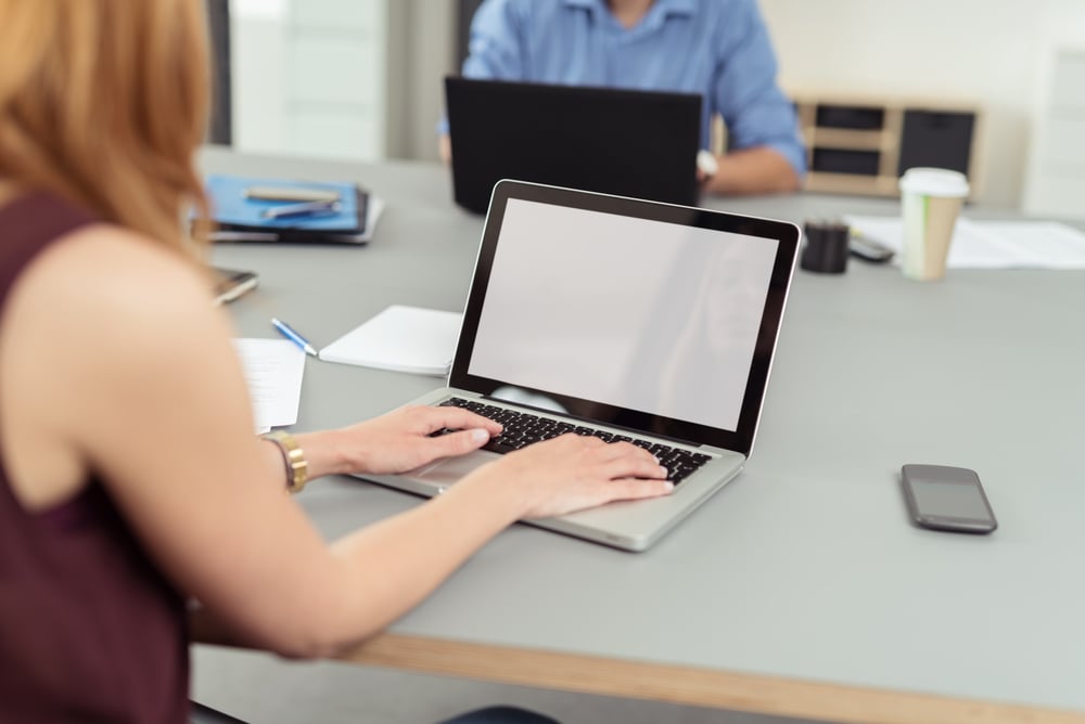 Modern business office where employees, man and woman, work on laptops and keep documents, files and mobile phones on the same shared desk-1