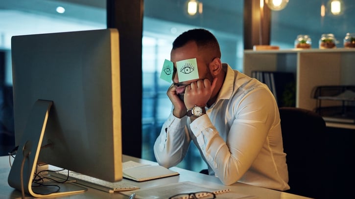 Müde Mitarbeiter sitzt im Büro am frühen Januarmorgen und kämpft mit Post-Holiday Blues nach den Feiertagen