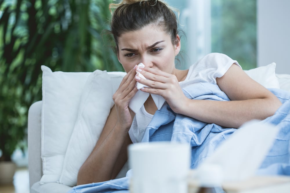 Femme malade au nez qui coule, allongée dans son lit