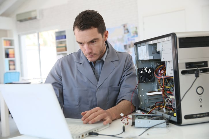Profesional de TI programando en una computadora portátil en un entorno de oficina.​
