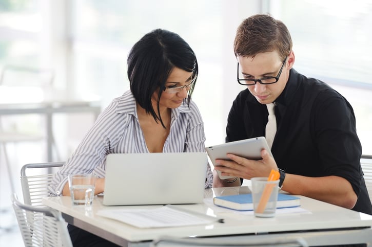 Payrollers working at office with paperwork using tablet and laptop