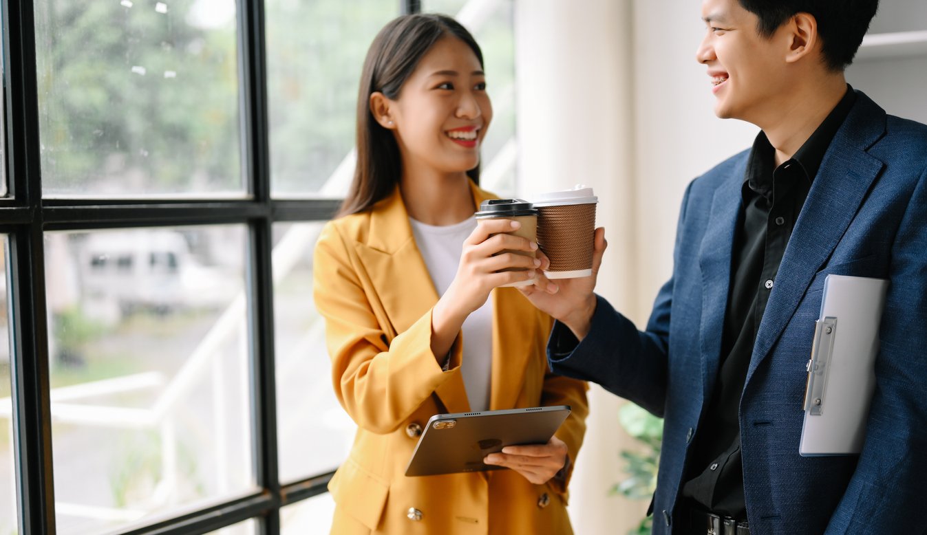 Two business workers standing and holding a coffee cup in a modern office