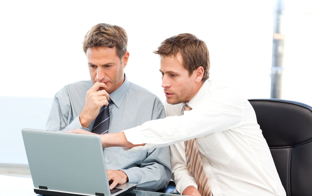 Two handsome businessmen working together on a project sitting at a table in the office