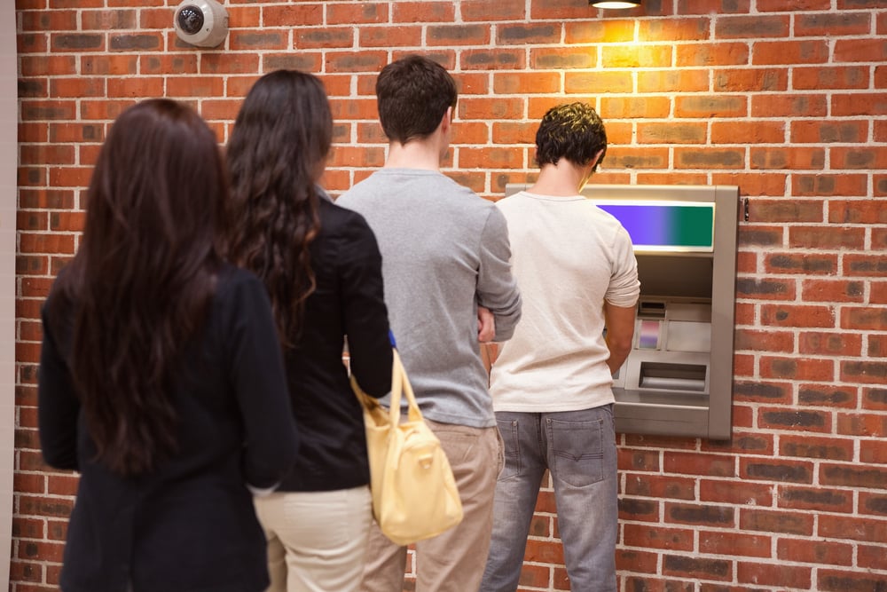 Young people queuing to withdraw cash in an ATM