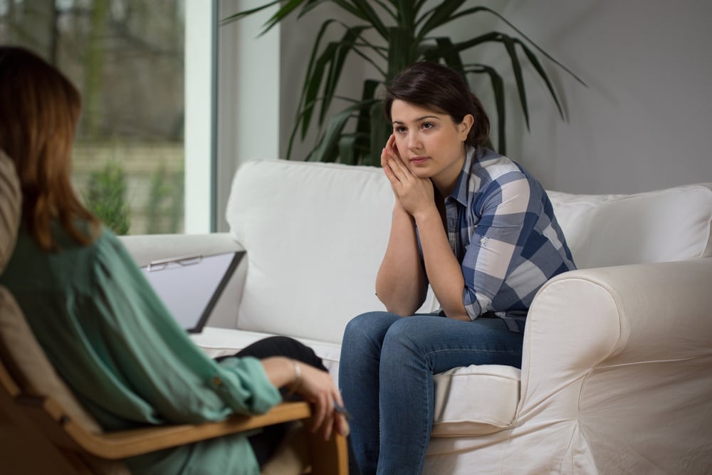 Young woman talking with psychologist about her problems