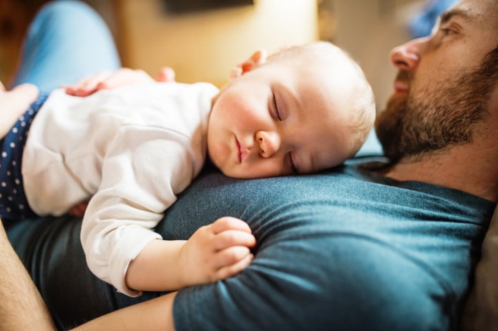 Väter nach der Geburt auf der Couch mit Neugeborenem