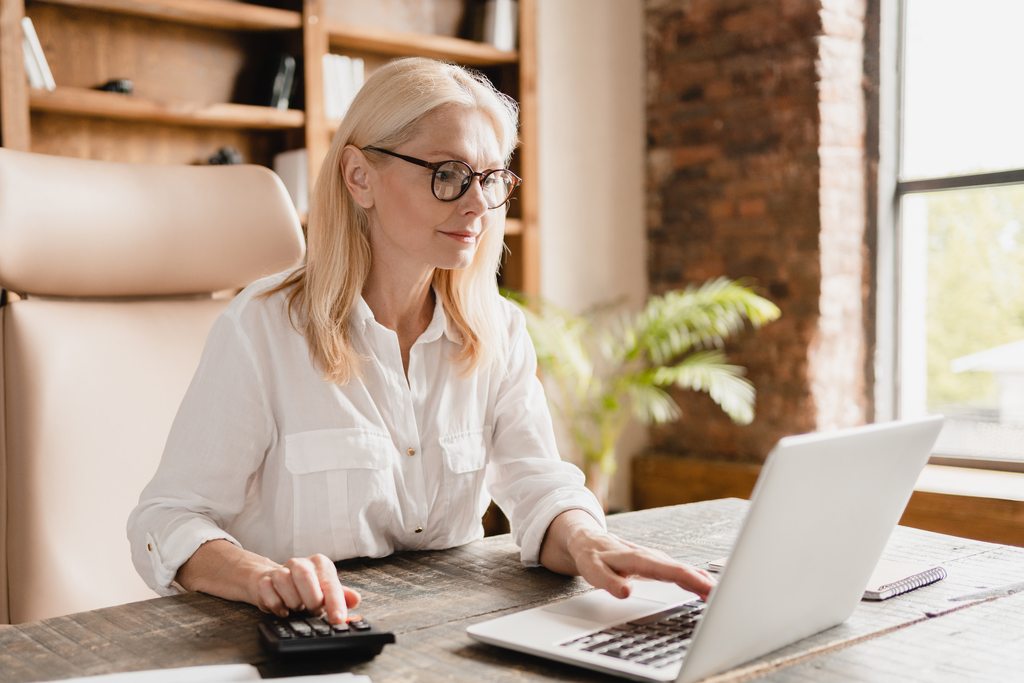 manager calculating PTO accrual of employees using laptop and calculator