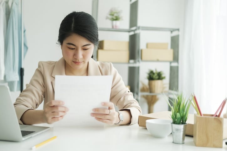 asian female employee reading warning letter at work