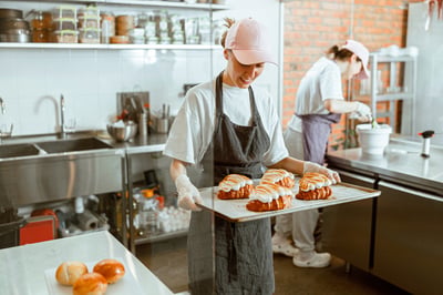 bakery worker holding tray with croissants