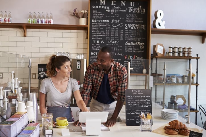 barista at a coffee shop showing the till to a new employee