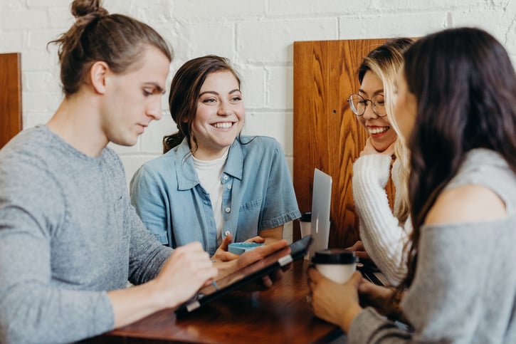 Groepje collega's zit om een tafel heen en lachen
