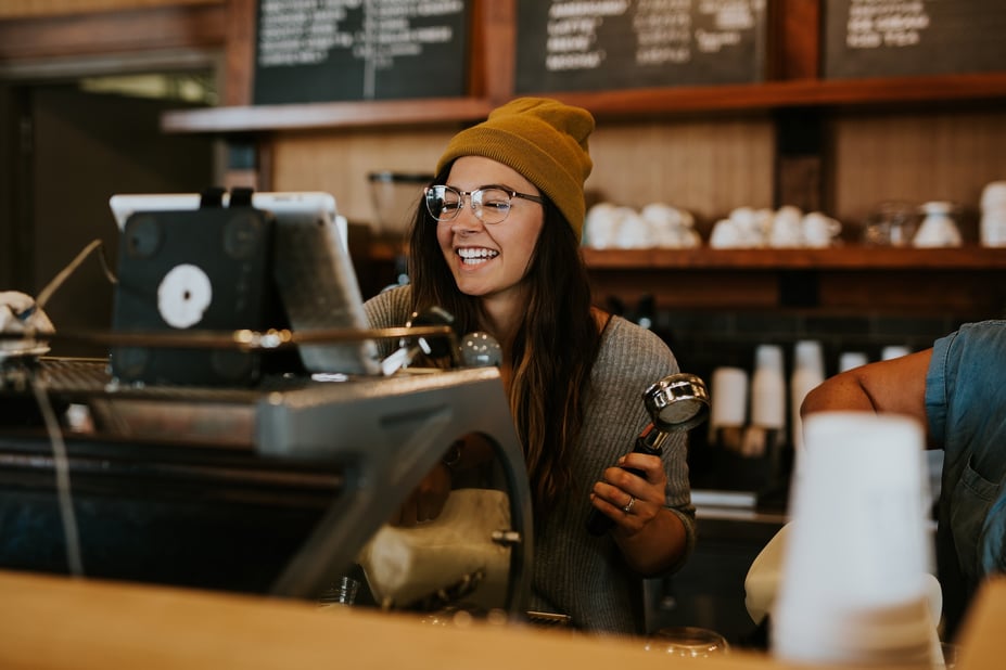 Vrouw staat voor koffie apparaat in cafe