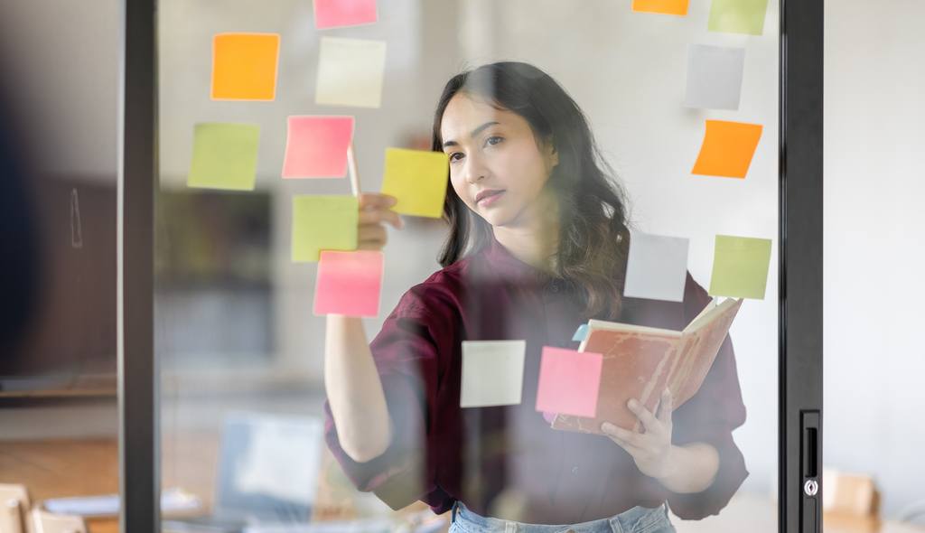 business female employee with many conflicting pri priorities arranging sticky notes 