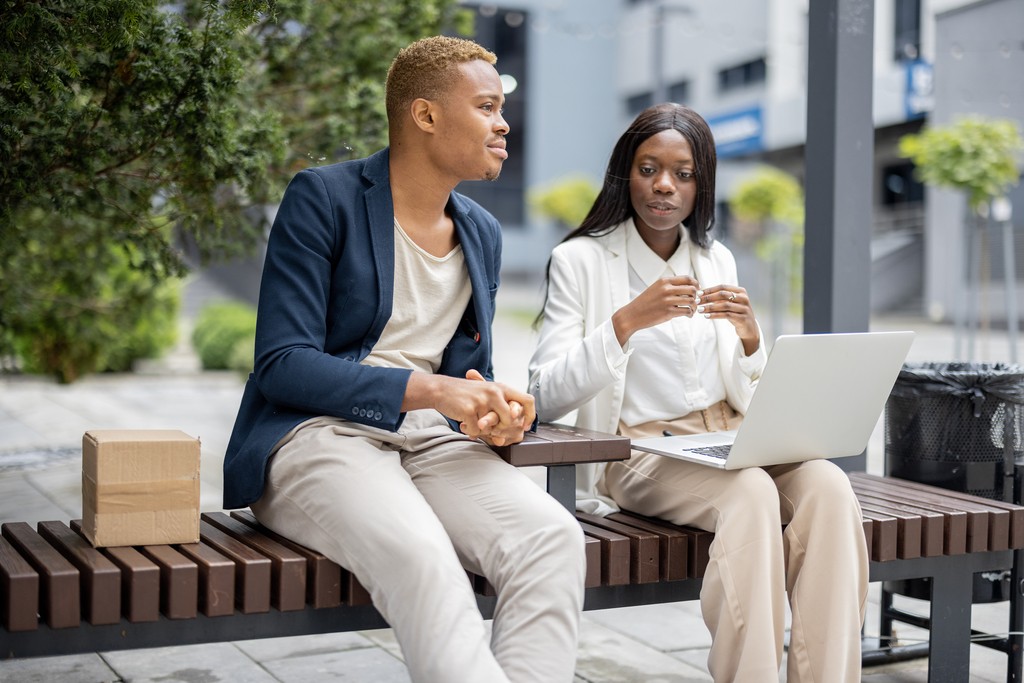 business people sitting on a bench having a meeting outside