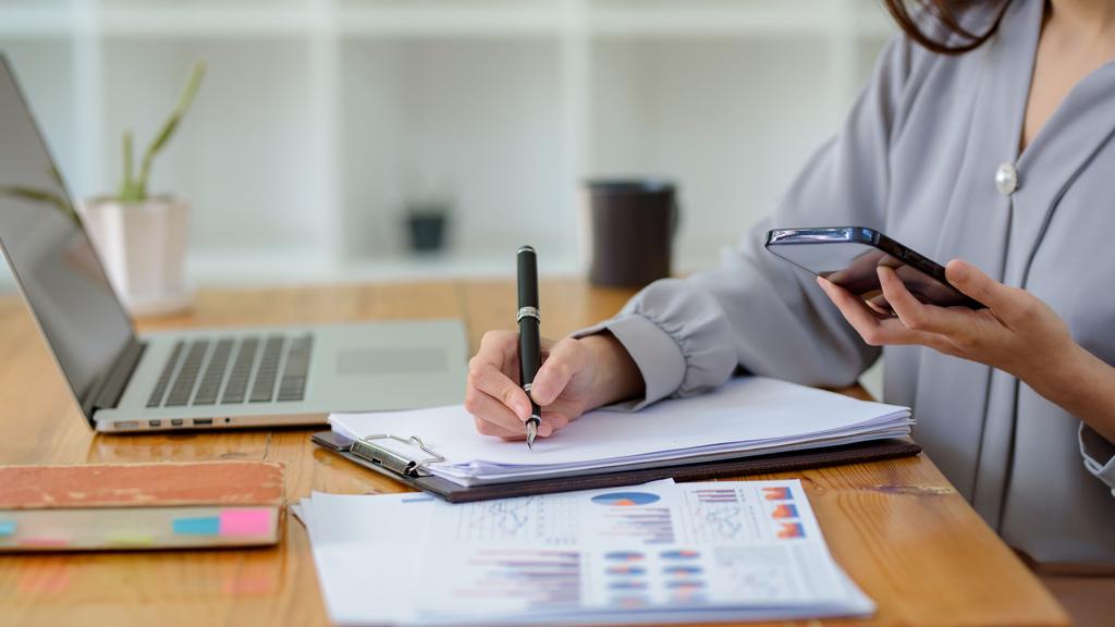 business woman using mobile phone to work and writing notes on paper