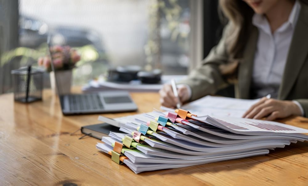 businesswoman working in stacks of paper files