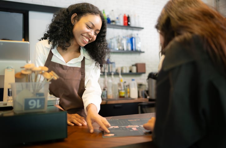 cafe barista showing menu to customer