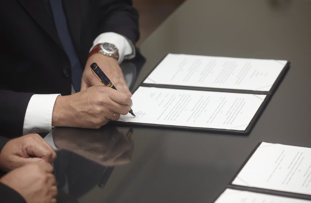 Ein Arbeitsvertrag mit festgelegtem Monatslohn liegt auf einem Tisch. Der Vertrag enthält wichtige Angaben zu Gehalt, Arbeitsstunden und möglichen Abzügen, die für Arbeitnehmer von Bedeutung sind.