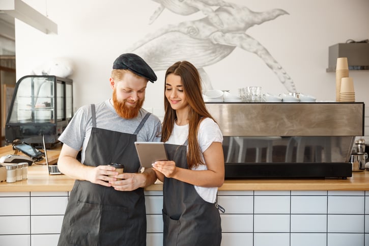 coffee shop manager baristas look at tablet